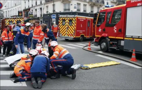  ?? THIBAULT CAMUS — THE ASSOCIATED PRESS ?? Firefighte­rs tend to a wounded person Saturday near the site of a gas leak explosion in Paris, France. A powerful explosion and fire apparently caused by a gas leak at a Paris bakery injured several people, blasted out windows and overturned cars, police said.