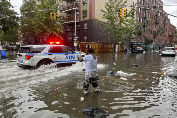  ?? JAKE OFFENHARTZ — THE ASSOCIATED PRESS ?? A man works to clear a drain in flood waters, Friday, Sept. 29, 2023, in the Brooklyn borough of New York. A potent rush-hour rainstorm has swamped the New York metropolit­an area. The deluge Friday shut down swaths of the subway system, flooded some streets and highways, and cut off access to at least one terminal at Laguardia Airport.