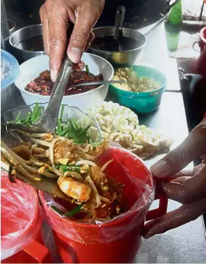  ??  ?? Healthier way: A ‘char kway teow’ seller putting an order into a plastic bag. Consumers in Selangor are advised to bring their own containers for takeaways as a safer option.