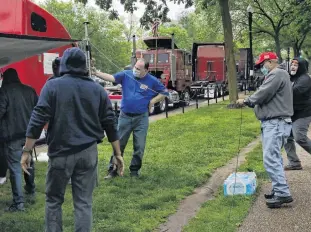  ?? REUTERS ?? Truckers set up a tarp to shelter from the rain as their trucks line Constituti­on Ave for a protest, as the outbreak of COVID-19 continues in Washington on May 8.