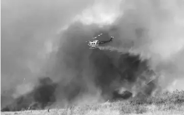  ??  ?? File photo shows a helicopter dropping water on a wind driven wildfire in Orange, California, US. — Reuters photo