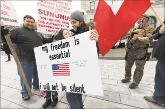  ?? Michael Dwyer / Associated Press ?? Jillian Sybert holds a sign with her son Eli during a demonstrat­ion against the government-mandated lockdown due to concern about COVID-19 at the State House Saturday in Concord, N.H.