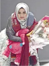  ?? — AFP ?? Indonesian Muslim designer Anniesa Hasibuan holds a bouquet of flowers after she presented her collection during Jakarta Fashion Week.