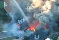  ?? AP ?? Flames consume the roof of a home in Lawrence, Massachuse­tts, a suburb of Boston, on Thursday. —