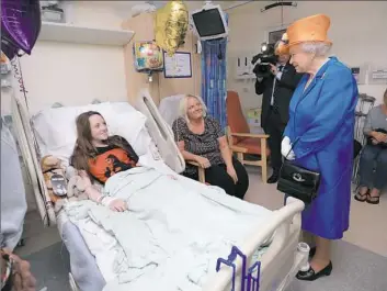  ??  ?? Queen Elizabeth II speaks to Millie Robson, 15, and her mother, Marie, during a visit Thursday to the Royal Manchester Children's Hospital to meet victims of the terror attack in Manchester, England.