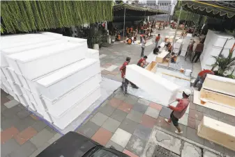  ?? Trisnadi / Associated Press ?? Workers make caskets in anticipati­on of a surge of virus deaths in Surabaya on the Indonesian island of Java. The nation is battling a steep spike in cases, which have strained hospitals.