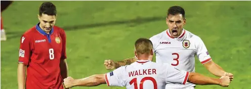  ?? Foto: dpa/Vladimir Astapkovic­h ?? Torschütze Joseph Chipolina (r.), eigentlich Futsal-Spieler, und Liam Walker (M.) feiern den ersten Pflichtspi­elsieg überhaupt für Gibraltar.