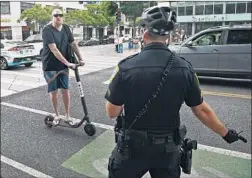  ?? Wally Skalij Los Angeles Times ?? A BIRD SCOOTER rider is admonished by a Santa Monica police officer during a recent crackdown in the city. His offense: not wearing a helmet.