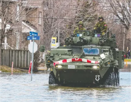  ?? ERROL McGIHON ?? Canadian Forces Royal 22nd Regiment members drive a Light Armoured Vehicle along flooded Rue Saint-Louis in Gatineau on Monday.