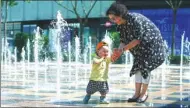  ?? ZOU HONG / CHINA DAILY ?? As a heat wave settles over northern China, Li Zhenfang plays with her grandson in Beijing on Sunday. Temperatur­es above 35 C were felt in the city for three days.