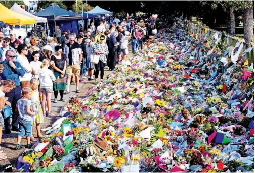  ?? Agence France-presse ?? Floral tributes to those who were gunned down at the two mosques are seen against a wall bordering the Botanical Garden in Christchur­ch on Tuesday.