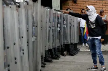  ?? Edilzon Gamez/Getty Images ?? An anti-Maduro demonstrat­or with his face covered points at Venezuelan National Police officers during a demonstrat­ion Tuesday against the government of Nicolas Maduro organized by supporters of Juan Guaido in Caracas, Venezuela.