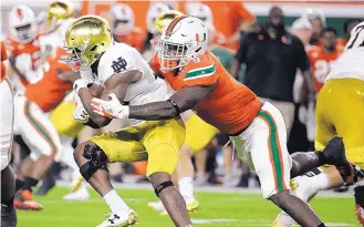  ?? LYNNE SLADKY/ASSOCIATED PRESS ?? Notre Dame running back Josh Adams, left, is tackled by Miami defensive lineman Chad Thomas during the first half of their Top-10 showdown Saturday night.