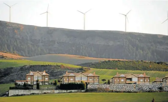  ??  ?? Vista de varias casas de Zariquiegu­i con los molinos de viento al fondo.