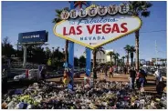  ?? JOHN LOCHER / ASSOCIATED PRESS ?? Flowers, candles and other items surround the famous Las Vegas sign Monday at a makeshift memorial for victims of a mass shooting.