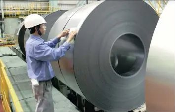  ?? FILE PHOTO: BLOOMBERG ?? A worker puts a label on manufactur­ed steel rolls at Baoshan Iron & Steel Company outside Shanghai. China’s steel oversupply may be dumped on world markets and is of great concern to global steel producers .