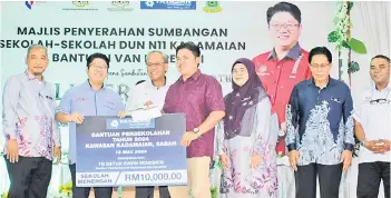  ?? ?? Ewon presenting the RM10,000 contributi­on to SMK Tambulion, represente­d by the school’s parent-teacher associatio­n chairman, Simon Sabalah.