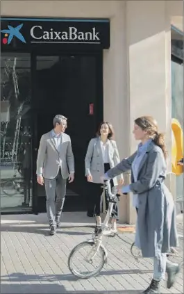  ?? ?? Unas personas pasean frente a una sucursal de CaixaBank.