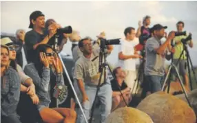  ?? Helen H. Richardson, Denver Post file ?? Jessica Kutz, with glasses, of Boulder, right, and others catch a glimpse of the partial eclipse as it peeked out from behind the clouds on May 20, 2012. Dozens of people gathered on the Boulder overlook on Highway 36 just southeast of Boulder to get a...