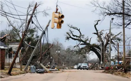  ?? AP PHOTO/STEW MILNE ?? On Jan. 13, cars carefully navigate around downed trees and power lines on Chestnut Boulevard in Selma, Ala., after a tornado passed through the area the day before.