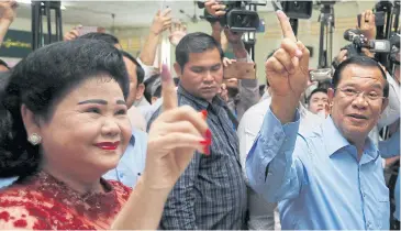  ?? REUTERS ?? Cambodia’s Prime Minister, Hun Sen, and his wife Bun Rany, show their stained fingers after voting yesterday.