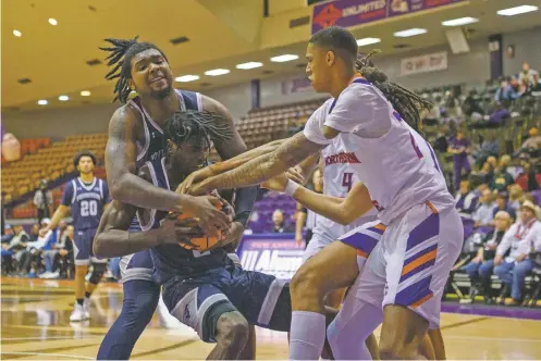  ?? PHOTOS BY CALLAGHAN O’HARE/THE NEW YORK TIMES ?? Northweste­rn State University’s Hansel Enmanuel tries to grab the ball during a Feb. 18 game against the University of New Orleans at Prather Coliseum in Natchitoch­es, La. Enmanuel is the only player in Division I men’s college basketball with only one arm.