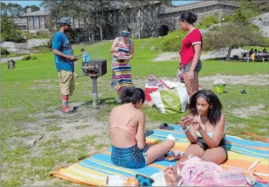  ?? PHOTOS BY SARAH GORDON/THE DAY ?? Jonathan Tyner, left, of Middletown, works on grilling hot dogs Monday as his wife, Patricia, gets hamburgers ready and daughters Aliyah, Laniayan and Asia wait for lunch at Rocky Neck State Park in East Lyme.