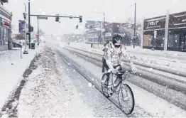  ?? MICAHEL CIAGLO/GETTY ?? A bicyclist makes his way down an icy and snowy street Sunday in Denver. The runways were closed just before noon Sunday at Denver Internatio­nal Airport.