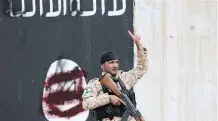  ?? AL- RUBAYE/ GETTY IMAGES ?? A member of the Iraqi security forces flashes a victory sign in front of a defaced Islamist flag in Tikrit Wednesday.