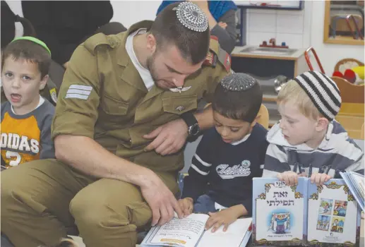  ?? (Gershon Elinson/Flash90) ?? A SOLDIER in an IDF conversion course interacts with children praying at their kindergart­en in 2013.