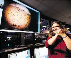  ??  ?? An engineer at NASA’s Jet Propulsion Laboratory is all smiles Monday as she stands next to an image of Mars sent from the InSight lander shortly after it landed on the red planet.