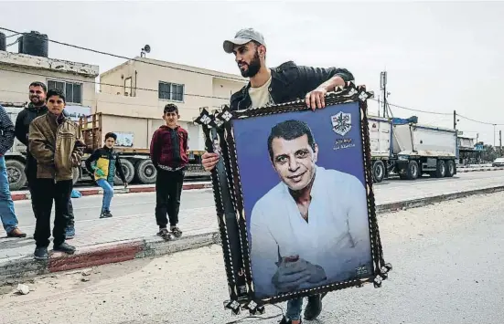  ?? SAID KHATIB / AFP ?? Un gazatí portando un retrato de Mohamed Dahlan a la llegada de vacunas emiratíes contra la covid gestionada­s por él, en marzo del 2021