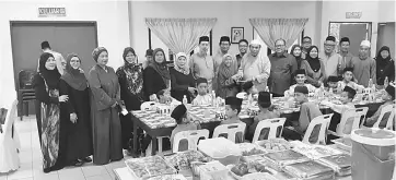  ??  ?? DUBS Miri adviser Datuk Ibrahim Din (standing ninth right) presents ‘duit raya’ to a resident. Victor is on his left.