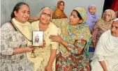  ?? — AP ?? Relatives mourn holding a portrait of Gurcharan Singh, one of the Indians whose bodies were found buried northwest of Mosul, in Jalal Usma village in Punjab on Tuesday.