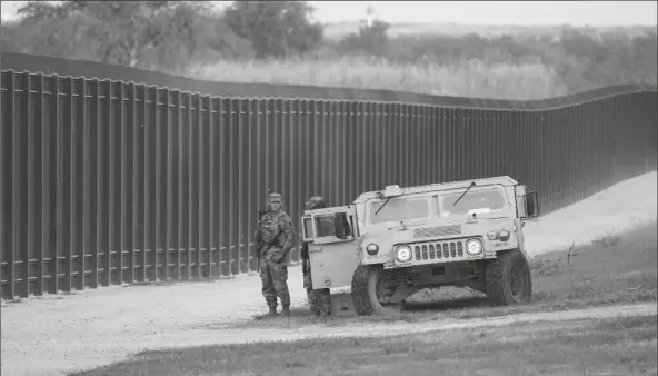  ?? ?? NATIONAL GUARDSMEN STANDS WATCH OVER A FENCE near the Internatio­nal bridge where thousands of Haitian migrants have created a makeshift camp, on Sept. 18, 2021, in Del Rio, Texas. Former Trump administra­tion officials have pressed Republican border governors to declare an “invasion” along the U.S.-Mexico border. Texas Gov. Greg Abbott on Wedneday announced “unpreceden­ted actions” to deter migrants coming to Texas.