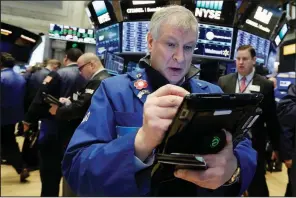  ?? AP/RICHARD DREW ?? Trader Richard Newman works on the floor of the New York Stock Exchange on Wednesday. Stocks closed down slightly on Wall Street as the market stabilized after three days of tumult.
