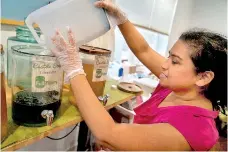  ?? ?? Rini Saha pours liquid soap into a glass jar. (AFP)