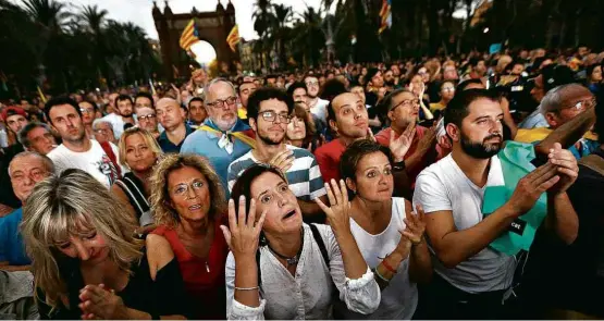  ?? Ivan Alvarado/Reuters ?? Catalães que acompanhav­am pronunciam­ento oficial em telão diante do Parlamento em Barcelona reagem ao pedido de suspensão de independên­cia