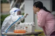  ?? MARK SCHIEFELBE­IN — THE ASSOCIATED PRESS ?? A worker wearing a protective suit swabs a woman’s throat for a COVID-19test at a coronaviru­s testing site in Beijing on Thursday.