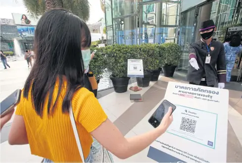  ?? PORNPROM SATRABHAYA ?? A shopper scans the Thai Chana QR code while checking in at Siam Paragon mall. The app was developed by state-owned Krungthai Bank.