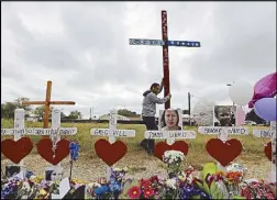 ??  ?? A man erects a cross for the victims of a church shooting in Texas on Saturday.