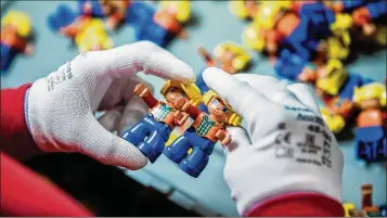  ?? PHOTOS BY AKOS STILLER / BLOOMBERG ?? An employee performs a quality control inspection on Lego Duplo figurines on the assembly line at the Lego plant in Nyiregyhaz­a, Hungary. On March 6, Lego announced its first revenue decrease in 13 years.