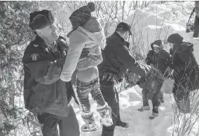  ?? PAUL CHIASSON / THE CANADIAN PRESS FILES ?? Somalian refugees are helped across the border into Canada last February near Hemmingfor­d, Que. Many recent migrants crossing illegally into Canada are Nigerian, which suggests word-of-mouth about Canada as a safe haven has continued to spread.