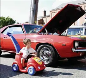 ?? JESI YOST — DIGITAL FIRST MEDIA ?? Roman Rhude, 2, of Boyertown parks his ride along side of cars on Reading Avenue, Boyertown, during the 11th Annual Cruise Night on July 28.