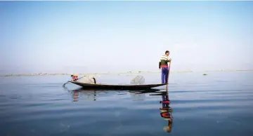  ?? — AFP photo ?? A fisherman rides his boat on Inle lake in Shan State.