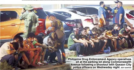  ?? BOY SANTOS ?? Philippine Drug Enforcemen­t Agency operatives sit at the parking lot along Commonweal­th Avenue following a shootout with Quezon City police officers on Wednesday night.