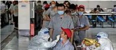  ?? AFP ?? Arbeitende in Wuhan lassen sich auf das Coronaviru­s testen.