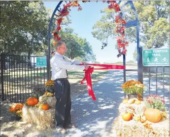  ?? Westside Eagle Observer/SUSAN HOLLAND ?? Neil Dye, pastor of the Decatur Seventh-day Adventist Church, cuts the ribbon to mark the opening of the church’s new 1.3-mile trail Sunday afternoon, Oct. 2. The trail, located behind the church on East Roller Avenue, is open to the public.