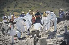  ?? Marcus Yam Los Angeles Times ?? WORKERS MOVE a casket as family members watch at a Tijuana cemetery. Many Mexicans with COVID- 19 are left to home remedies and relatives’ care.