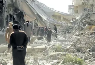  ?? THE ASSOCIATED PRESS ?? This undated frame grab from a video posted online on Monday by the Aamaq News Agency, the media arm of Islamic State, shows people inspecting damage from airstrikes and artillery shelling in the northern Syrian city of Raqqa.